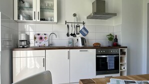 Eine moderne Küche mit weißen Schränken, einem eingebauten Backofen und einer Kaffeemaschine.