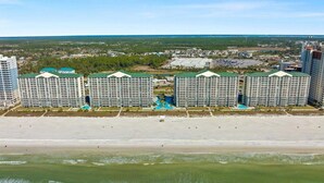 Un hotel frente al mar con varios edificios altos, una piscina y una playa en primer plano.