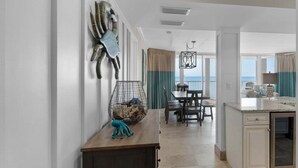 Una cocina moderna con comedor, un amplio ventanal con vista al mar y una escultura decorativa de cangrejo en la pared.