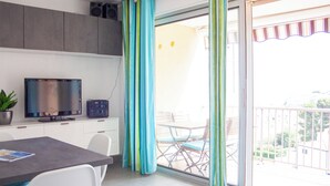 Eine moderne Küche mit Fernseher, einer Topfpflanze und einem Essbereich inklusive Tisch und Stühlen.