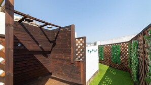 A wooden deck with a built-in shower, surrounded by a wooden fence with lattice panels and greenery. - Suite Home Sagrada Familia (Barcelona)