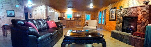 A cozy living room with a leather sofa, a coffee table, and a stone fireplace. - The Great Escape - Near everything yet off the beaten path (Shenandoah)