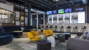 A modern bar area with a bar counter, multiple TVs, and a variety of seating options including sofas and chairs. - Aloft by Marriott Dallas DFW Airport Grapevine (Coppell)