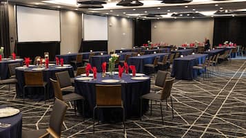 A conference room with round tables, chairs, and a projector screen.