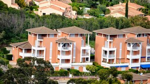 A residential building with multiple balconies and a central courtyard. - SEA VIEW-STUDIO 2 PERSONS- Classified 3 *- TERRASSE ABRITEE -CLIM-PARKING PRIVE (Le Lavandou)
