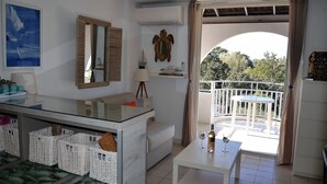 A modern living room with a balcony, a sofa, a dining table, and a kitchen area with baskets. - SEA VIEW-STUDIO 2 PERSONS- Classified 3 *- TERRASSE ABRITEE -CLIM-PARKING PRIVE (Le Lavandou)
