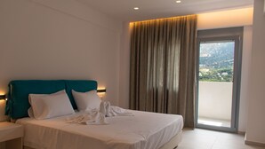 A hotel room with a large bed, a nightstand, a window with curtains, and a view of a mountainous landscape. - Villa Marine, New Luxury Villa with Amazing Seaview & Private Pool (Bali)
