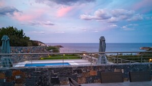 An outdoor patio with a pool, stone walls, and a view of the sea. - Villa Marine, New Luxury Villa with Amazing Seaview & Private Pool (Bali)