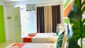 A hotel room with two beds, a window with curtains, an air conditioning unit, and a green plant. - Islands Stay Hotel Mactan (Lapu-Lapu)