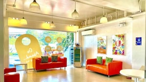 A modern lobby with two red sofas, a vending machine, and a small table. - Islands Stay Hotel Mactan (Lapu-Lapu)