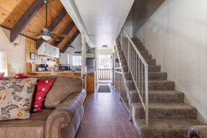 A cozy living room with a brown leather couch, a wooden ceiling, and a staircase leading to an upper level. - Mammoth View Villas 20-Nice townhome close to the Village (Mammoth Lakes)