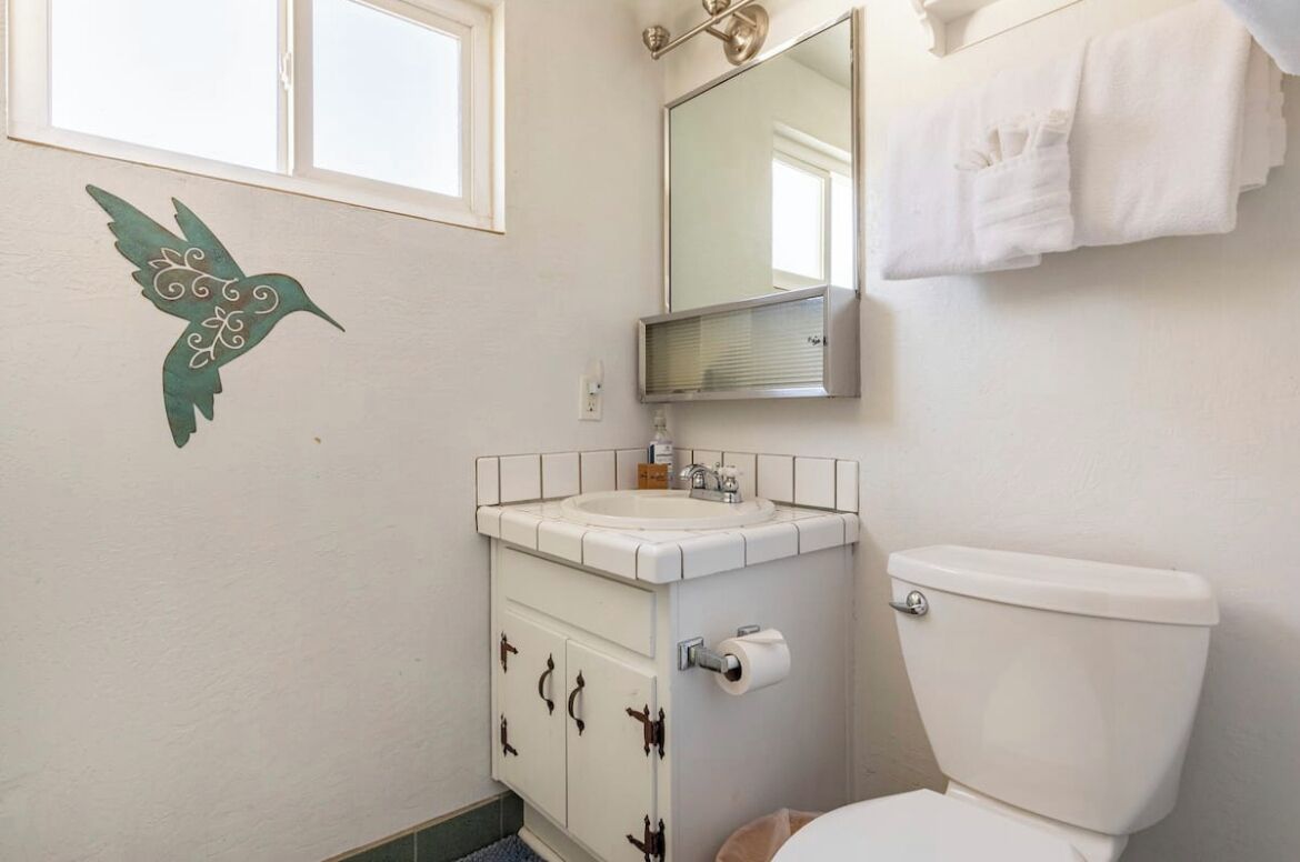 A bathroom with a white sink, a toilet, and a mirror above the sink.