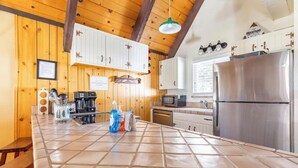 A kitchen with wooden walls, white cabinets, a stainless steel refrigerator, and a tiled countertop. - Mammoth View Villas 20-Nice townhome close to the Village (Mammoth Lakes)