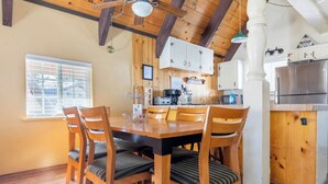 A wooden dining table with six chairs, a kitchen area with white cabinets, a refrigerator, and a window with blinds. - Mammoth View Villas 20-Nice townhome close to the Village (Mammoth Lakes)