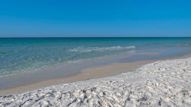 Uma praia com águas turquesa cristalinas e uma faixa de areia.