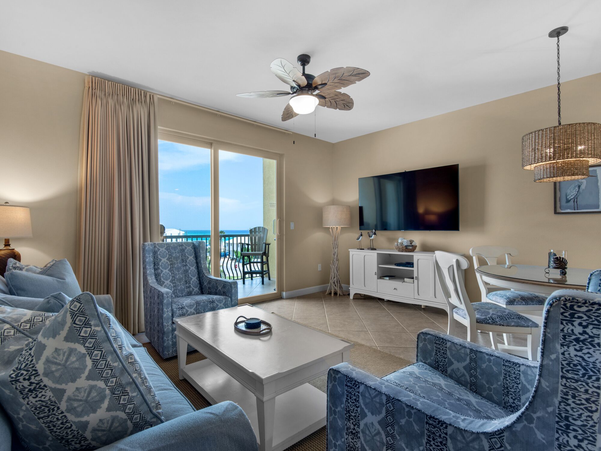 A modern hotel room with a balcony, a flat-screen TV, and a ceiling fan.