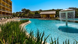 A swimming pool with a fountain, lounge chairs, and a building with balconies. - Balcony Views of the Gulf, Zero-Entry Pool, Free Beach Chair Service (Miramar Beach)