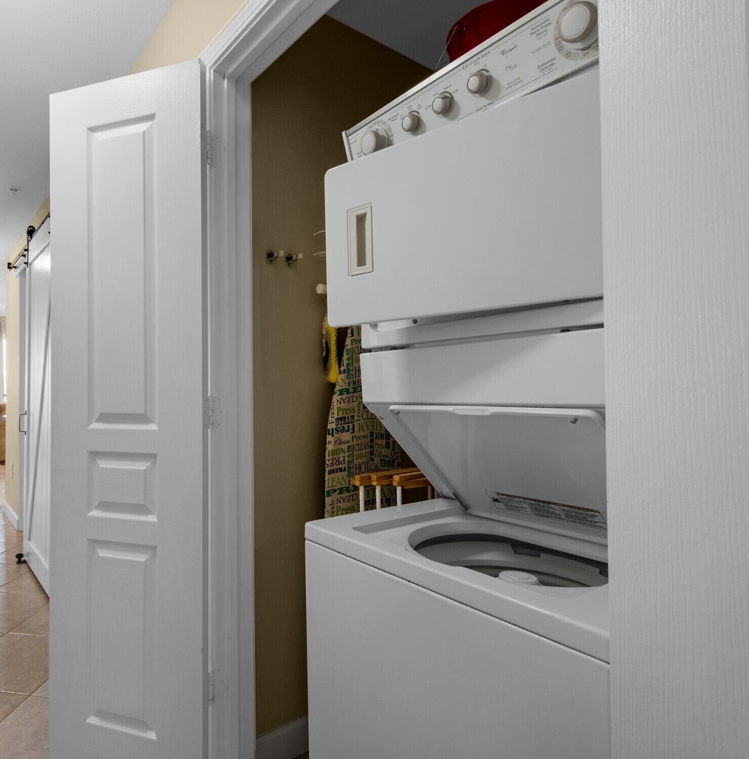 A laundry room with a front-loading washer and dryer, a door, and a wall with a poster.