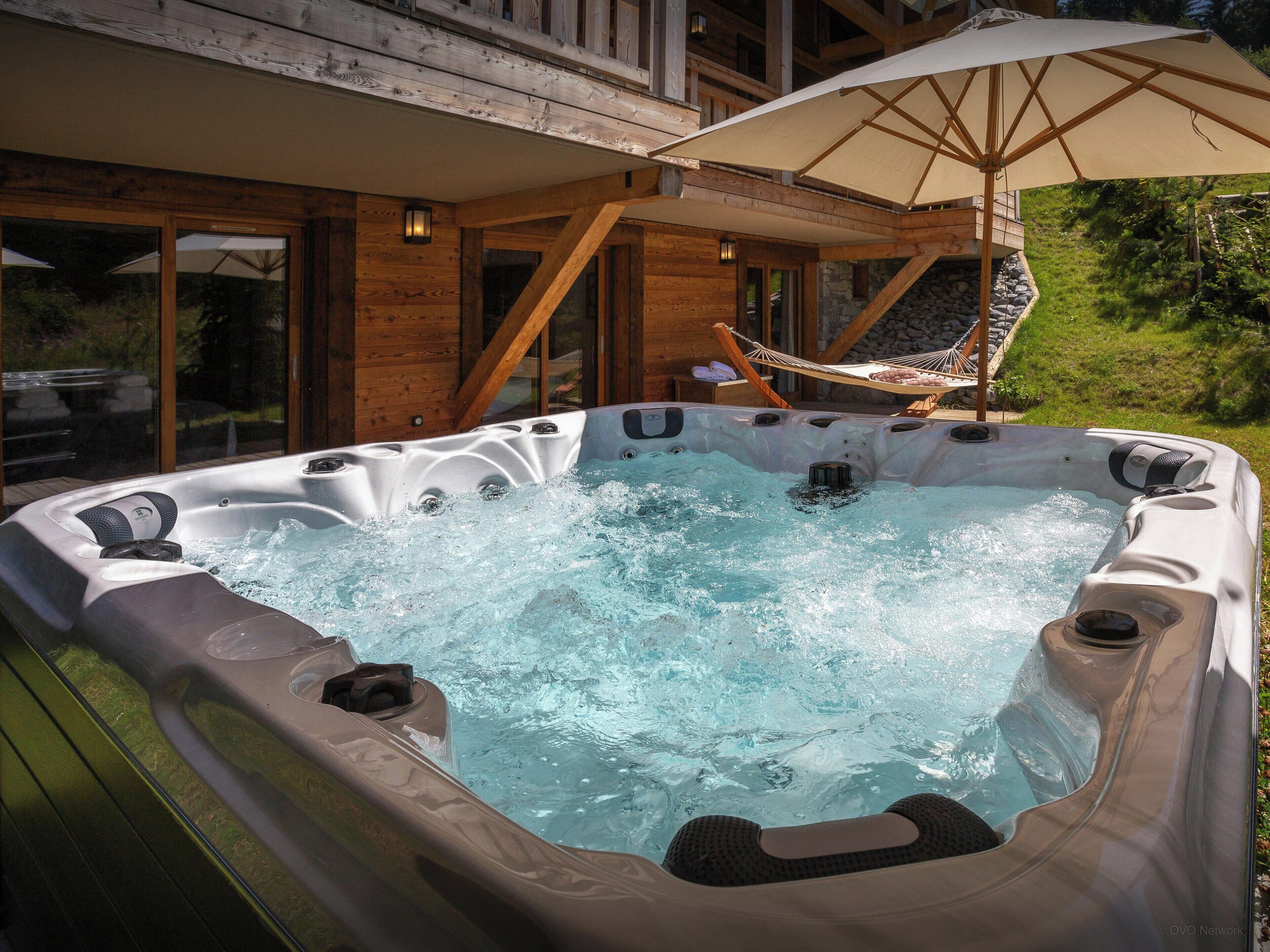 Un jacuzzi con terraza de madera y una hamaca.