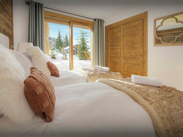 Een hotelkamer met een groot bed, een houten kledingkast en uitzicht op een besneeuwd landschap door het raam.