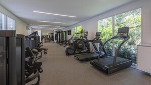 Une salle de sport équipée de tapis de course, de vélos elliptiques et d’appareils de musculation.