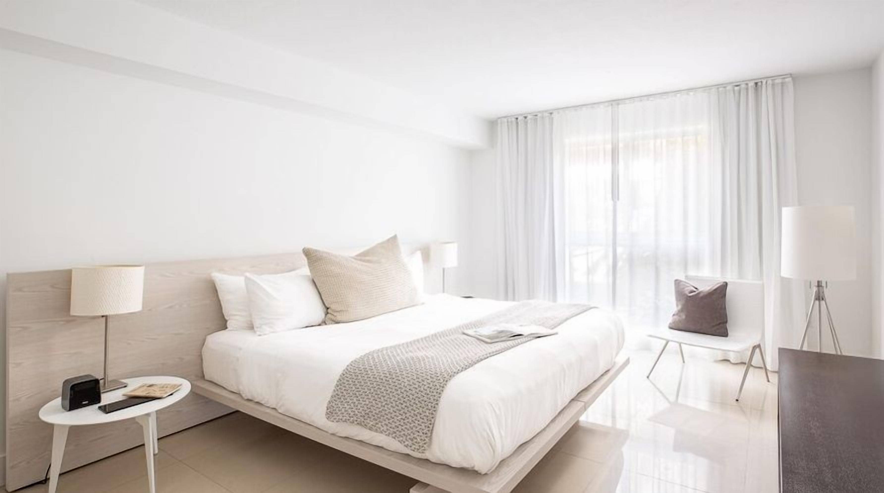 A modern hotel room with a large bed, bedside tables, a desk, and a chair.