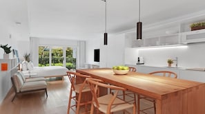 Uma cozinha moderna com uma mesa de jantar de madeira, cadeiras e uma tigela de frutas.