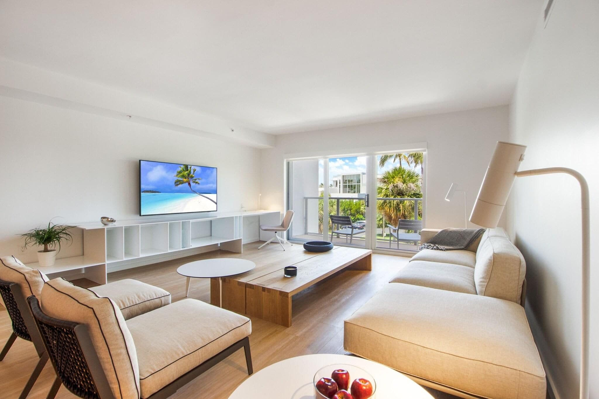 Una sala de estar moderna con un televisor de pantalla plana, un sofá, una mesa de centro y un comedor.
