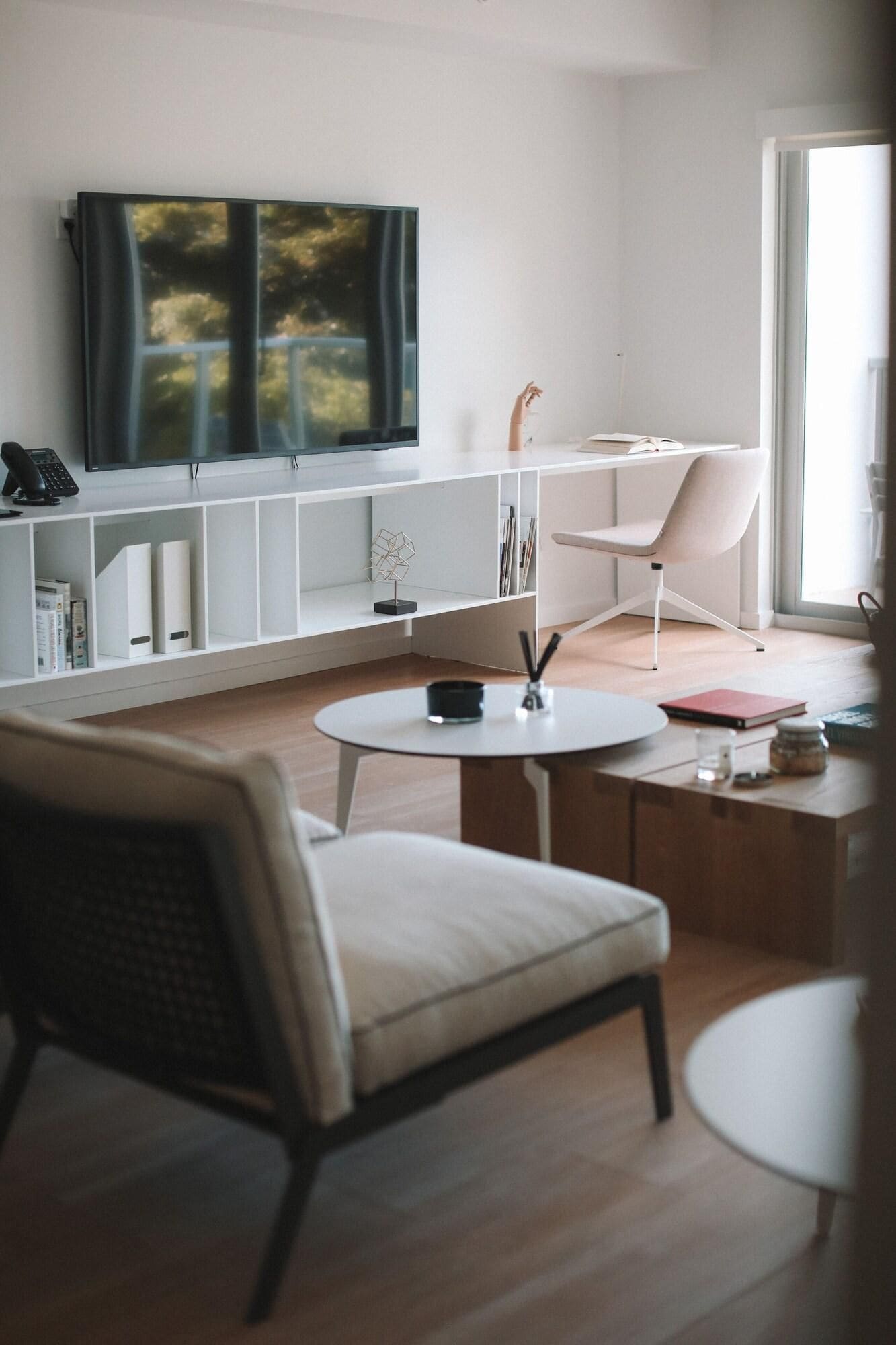 A modern living room with a flat-screen TV, a white sofa, a round coffee table, and a bookshelf.