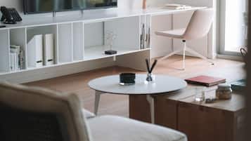 A modern living room with a flat-screen TV, a white sofa, a round coffee table, and a bookshelf.