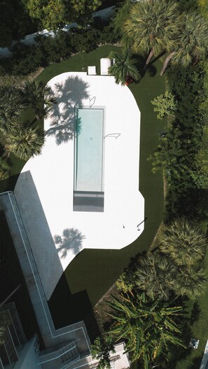 An aerial view of a swimming pool surrounded by lush greenery and a white building. - Beach Haus Bal Harbour (Bal Harbour)