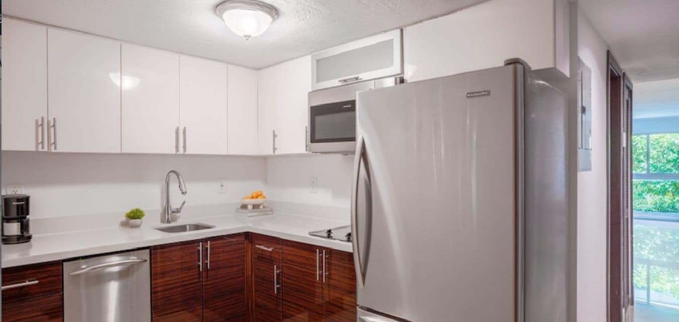 A modern kitchen with white cabinets, a stainless steel refrigerator, a microwave, and a dishwasher.
