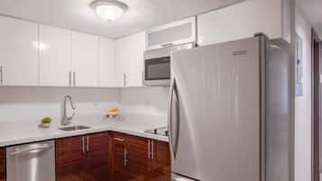 A modern kitchen with white cabinets, a stainless steel refrigerator, a microwave, and a dishwasher.