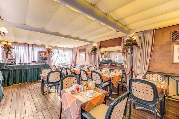 A dining area with tables and chairs, a buffet counter, and a wooden floor. - Condominio Monti (Rome)