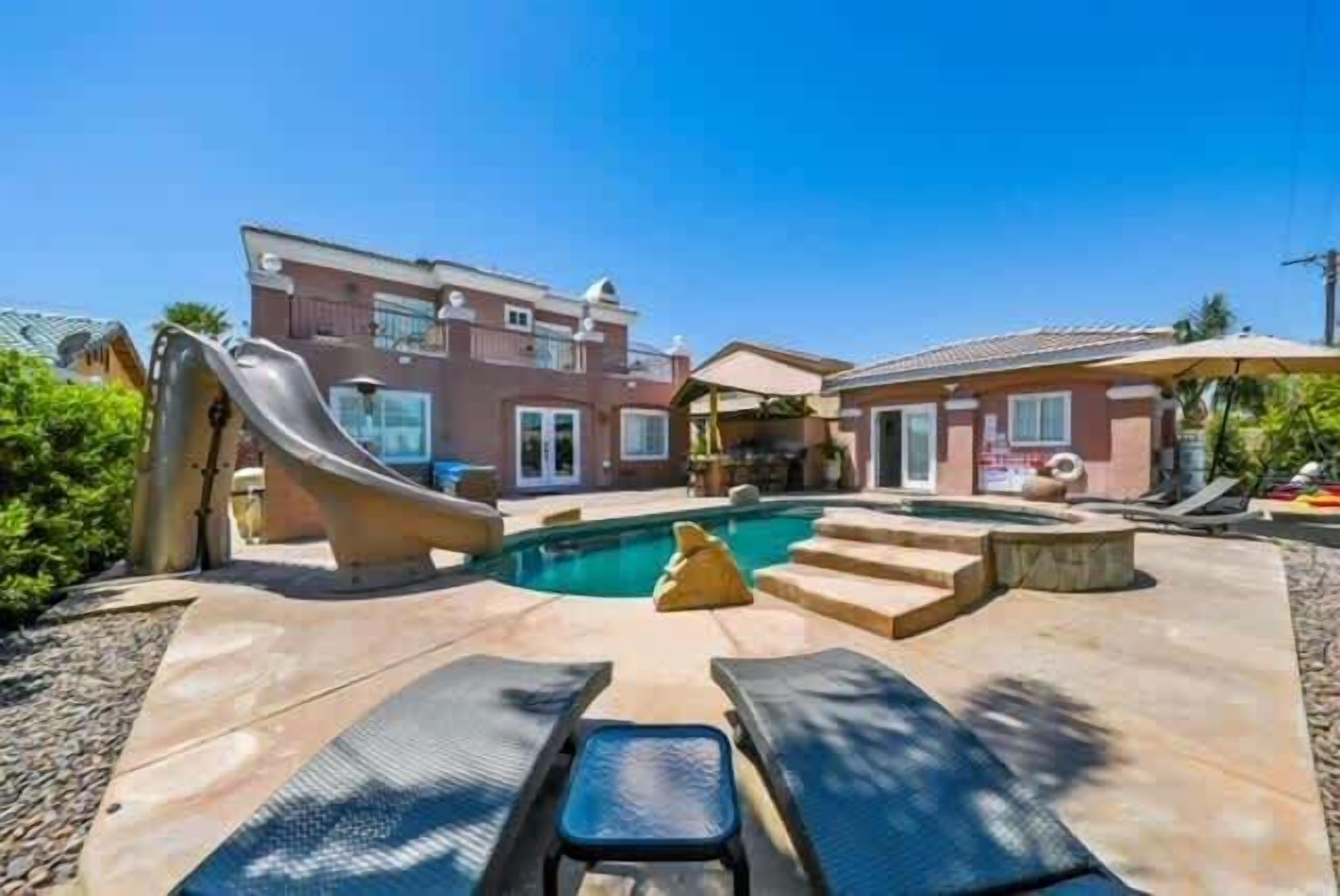 A residential property with a swimming pool, a slide, and a covered patio area.