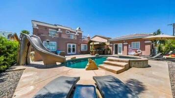 A residential property with a swimming pool, a slide, and a covered patio area.