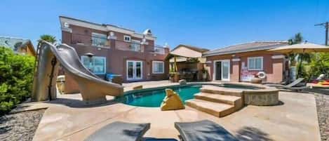 Une propriété résidentielle dotée d’une piscine, d’un toboggan et d’un patio couvert.