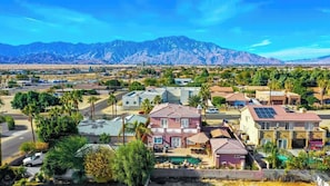 A residential area with houses, a swimming pool, and mountains in the background. - Fun For Everyone!  Family Friendly Pool Home! (Thousand Palms)