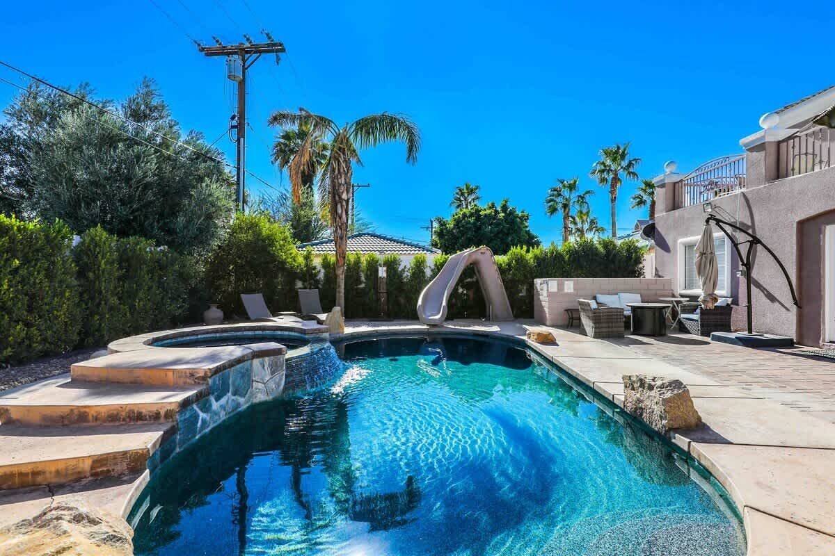 A swimming pool with a hot tub, surrounded by a patio area with outdoor furniture.