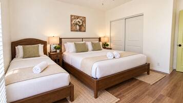 Habitación de hotel con dos camas, un ventilador de techo, un cuadro y una puerta.