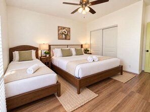 A hotel room with two beds, a ceiling fan, a painting, and a door. - Fun For Everyone!  Family Friendly Pool Home! (Thousand Palms)