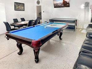 A pool table with a blue felt surface, surrounded by black leather chairs. - Fun For Everyone!  Family Friendly Pool Home! (Thousand Palms)