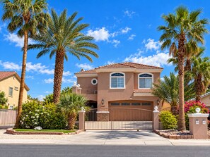 A two-story house with a brown facade, a garage, and a gated driveway.