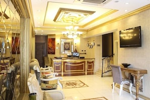 A hotel lobby with a reception desk, seating area, and a television mounted on the wall. - Marmara Deluxe Hotel (Istanbul)