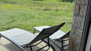 A patio area with two lounge chairs and a table, a stone wall, and a view of a grassy field. - Spacious, bright apartment close to the bay's beaches (Quiberon)