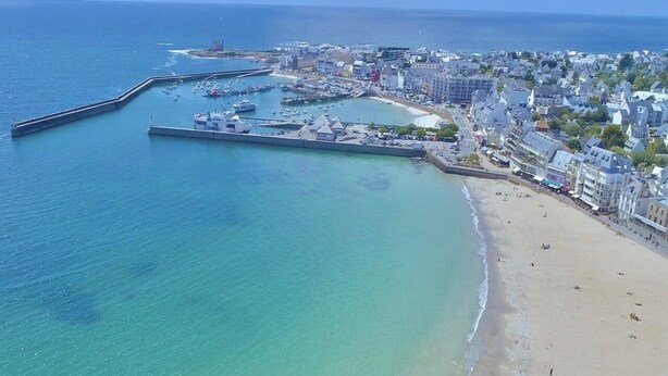 An aerial view of a coastal town with a sandy beach, a marina with boats, and buildings along the shore. - Spacious, bright apartment close to the bay's beaches (Quiberon)