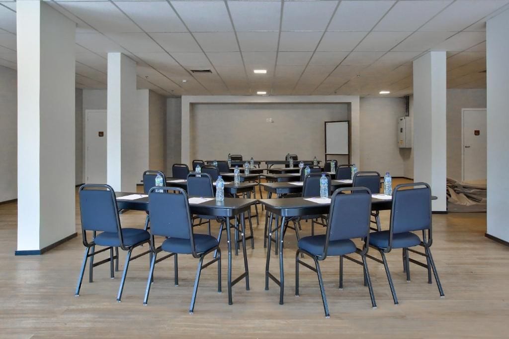 A conference room with multiple tables and chairs, equipped with water bottles.