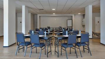 A conference room with multiple tables and chairs, equipped with water bottles.