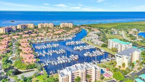 Un port de plaisance où sont amarrés de nombreux bateaux, entouré d’immeubles résidentiels et offrant une vue dégagée sur l’océan.