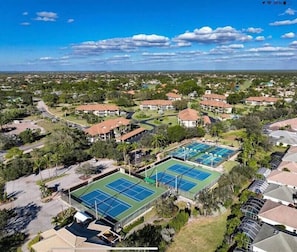 A residential area with multiple houses, a tennis court, and a parking lot.